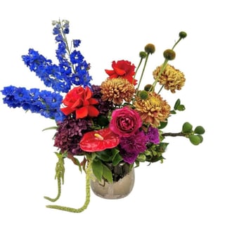 Binta - Gold ceramic vase arrangement featuring orange disbuds, premium red roses, blue delphinium, hydrangea and anthurium.