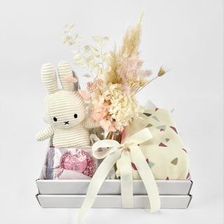Gift hamper for new baby girl with baby blanket, preserved flowers in vase and miffy bunny with chocolate.