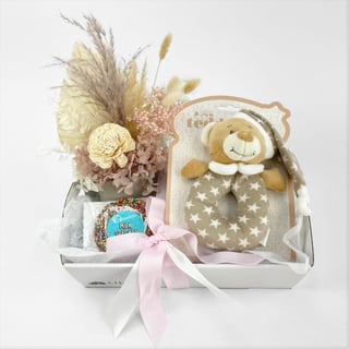 Petite preserved flower arrangement with baby rattle and chocolate gift hamper for newborn baby.