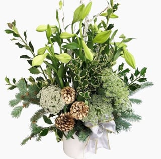 Christmas Lily, Pine Cone and christmas foliage arrangement in white ceramic