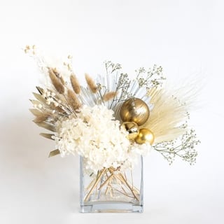 Christmas themed dry and preserved flower arrangement in clear vase.