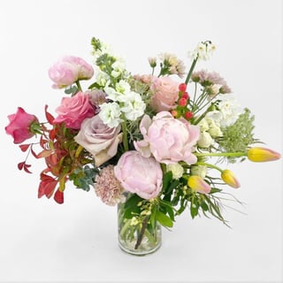 Frangrant bouquet in vase filled with different soft tones of roses, peonies, tulips, queen annes lace, stock, carnations and chrysanthemums.