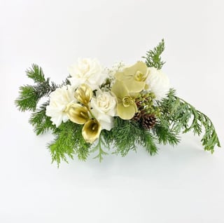 Low lying white rose, gold calla lily and phalaenopsis orchids with pine cones, babies breath and fresh pine arrangement in low round ceramic pot.