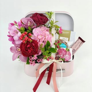 Suitcase gift hamper with roses, cymbidium orchids and seasonal flowers to suit. Personalise with `Thank you`, `Birthday` message