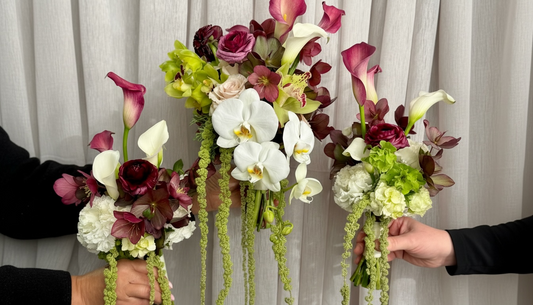 Burgundy, white and green bridal bouquet featuring calla lilies, orchids, ranunculus, hellebore and trailing amaranthus