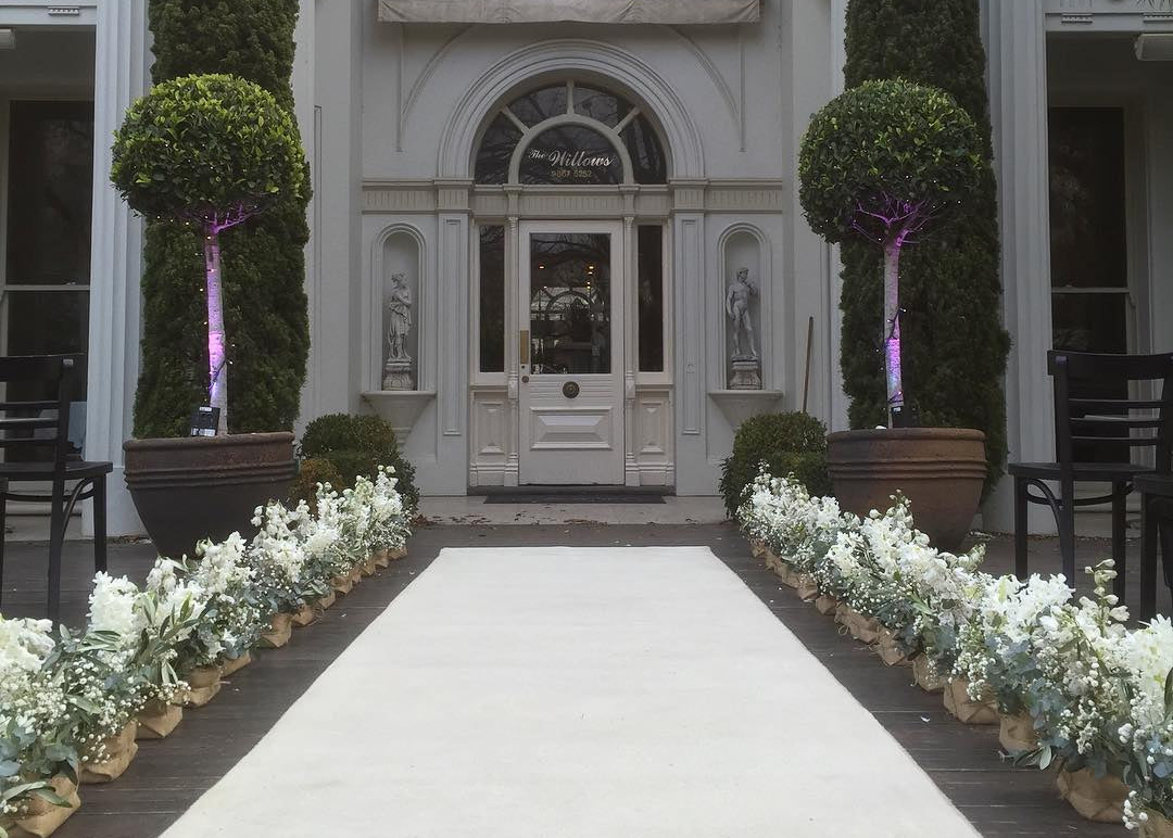 Decorative entrance with floral arrangements and potted plants in front of a building.