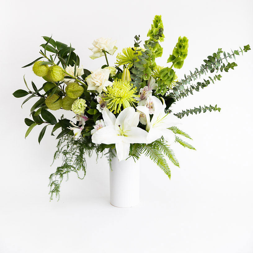 Flower bouquet arrangement with green and white lilies roses disbuds swanfruit carnation flowers in a white vase