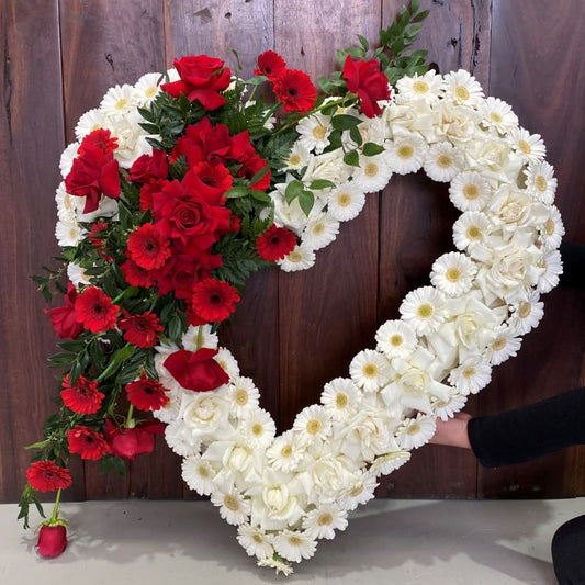Heart-shaped flower arrangement with red and white roses and gereras