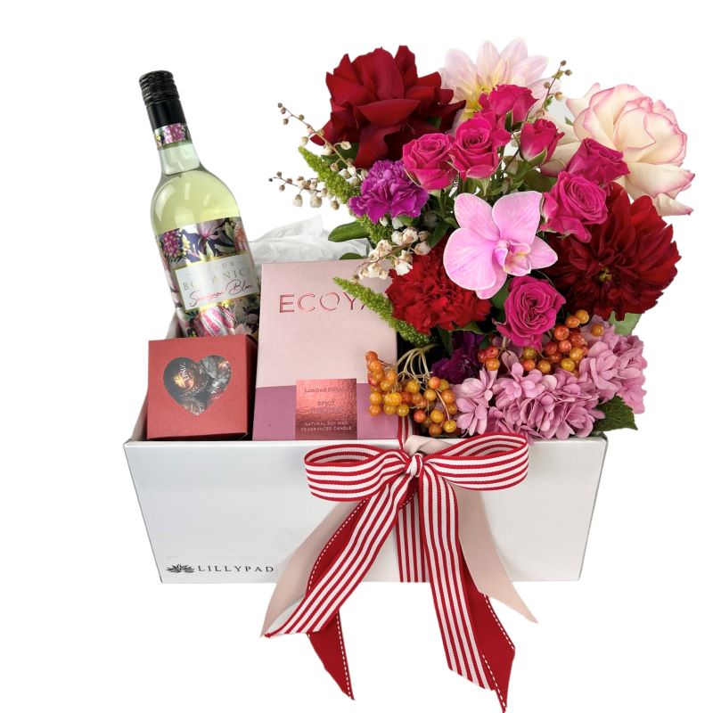 Rose, hydrangea, dahlia and seasonal flowers in ceramic vase with white wine, chocolates and candle