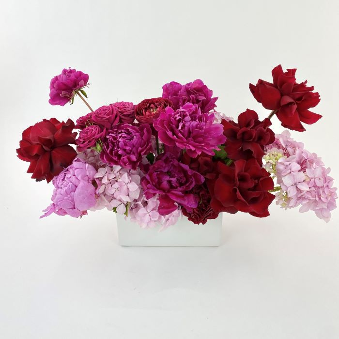 Low lying premium arrangement of various tones of pink, white and red roses, peonies and hydrangea