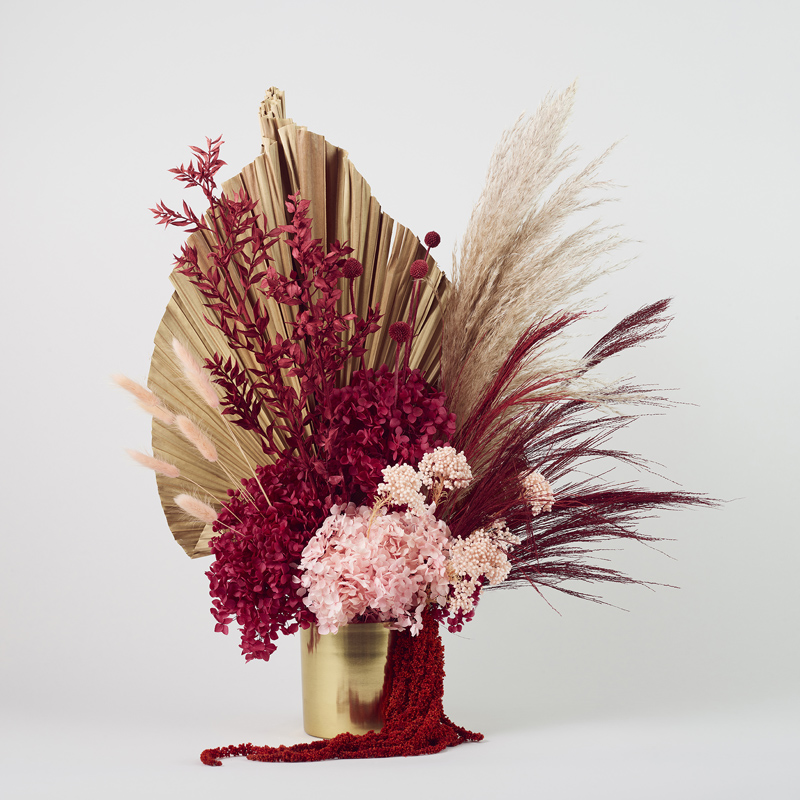 Rich jewelled with neutral dried and preserved flower arrangement in gold vase, features hydrangea, pampass, palm and amaranthus.