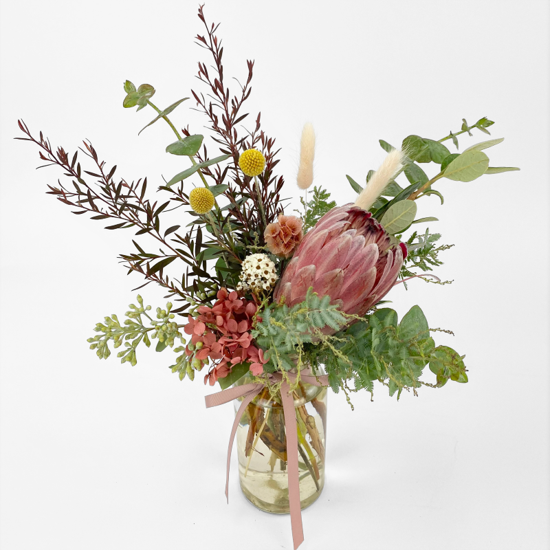 Petite vase arrangement featuring protea (or feature seasonal native) with billy buttons, bunny tails and seasonal foliage.