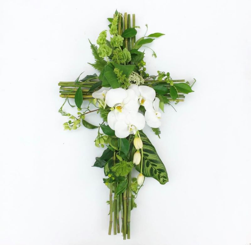 Funeral sympathy cross, hand made cross of bamboo featuring spray of white orchids, tulips and seasonals.