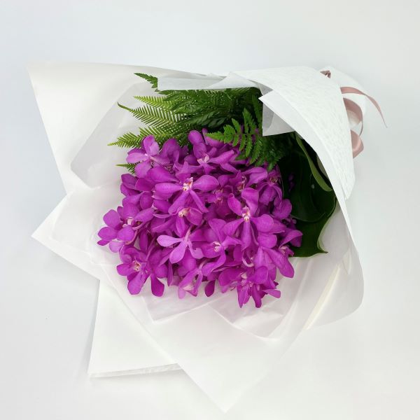 Bouquet of hot pink vanda orchids with lush tropical greenery.